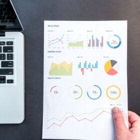 Detailed charts and graphs on a document next to a laptop, representing data analysis.